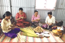 អ្នកស្រី នាង ភឿង (ទីពីរ ពីស្តាំទៅឆ្វេង) ណែនាំអ្នកម្តាយទាំងឡាយ បងៗ ស្រីនៅឃុំ អូឡឹម ស្រុក ទ្រីតូន (ខេត្ត អានយ៉ាង) ពីរបៀបវេចនំក៏ដូចជារបៀបលាយគ្រឿងផ្សំត្រៀមរៀបចំវេចនំ កាតំ